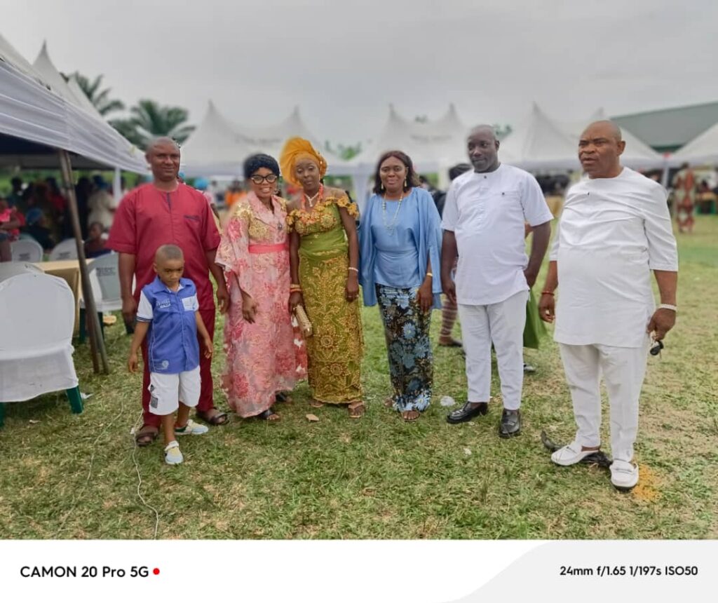 OREOSA92 members and a child posing on the grass at an outdoor event with marquee tents in the background